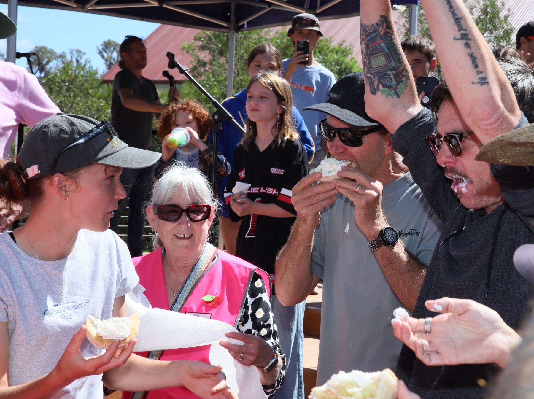 People eating cream-covered treats during an Applefest competition
